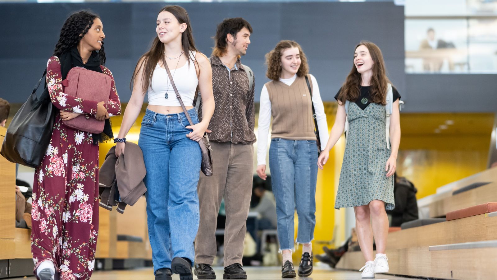 Five cheerful and diverse young people walking together.