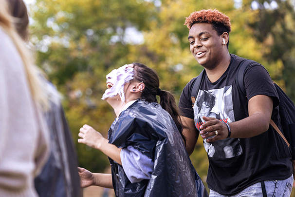 a student laughing after being hit with a pie during an event