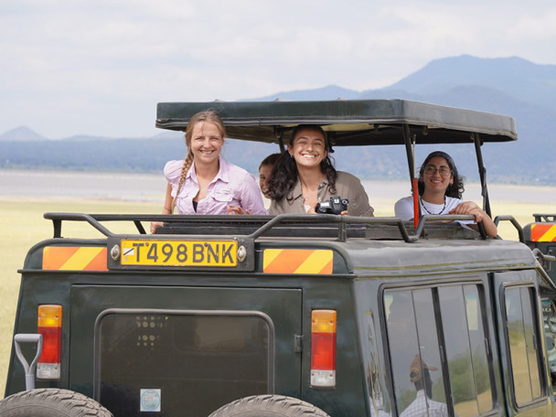 Three people looking out of a safari jeep in the African plains.